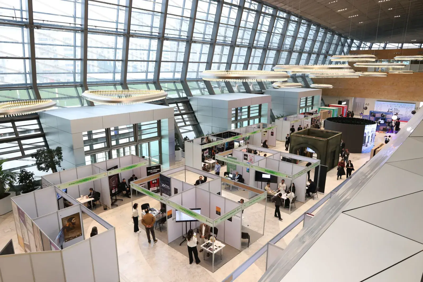 Wide view of an exhibition hall with branded stands and visitors