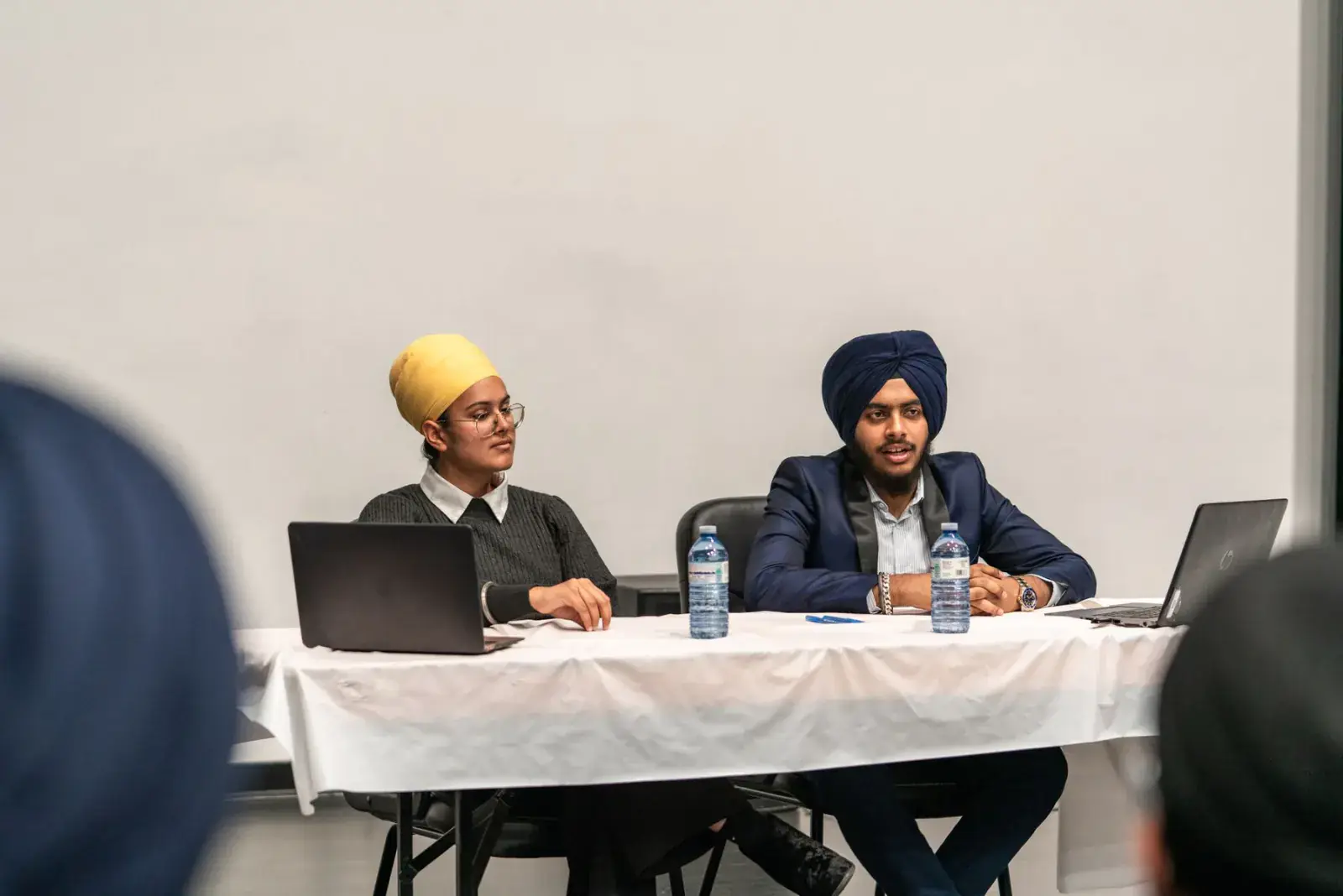 Panel speakers seated at a table with microphones and laptops