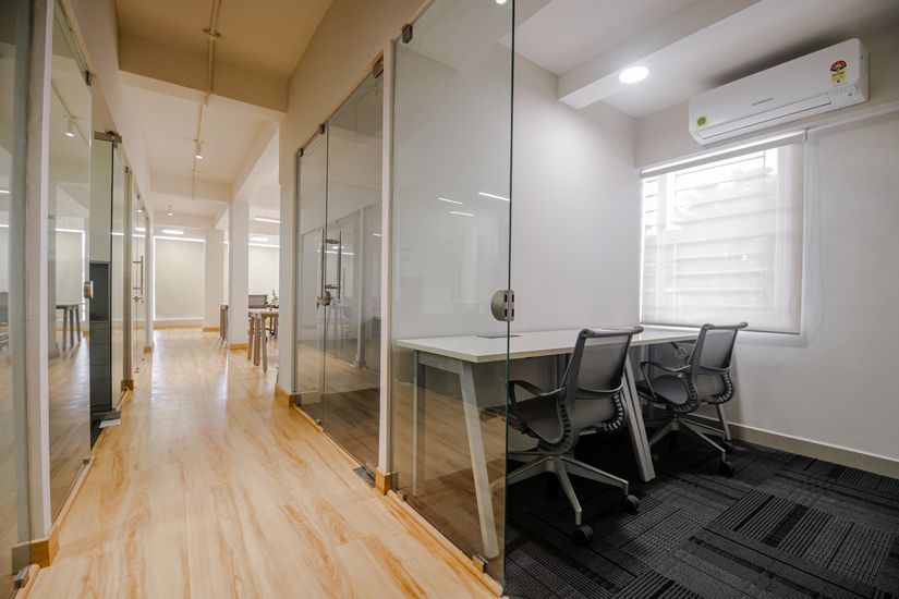 Glass-partitioned cabins along a corridor in the NextGen Events Group office